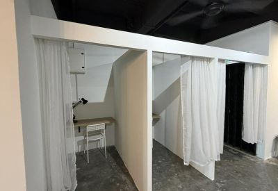 Individual work cubicles partitioned by white curtains for privacy.