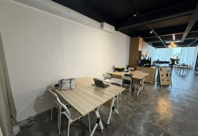 Open-plan office area with light wood desks and black industrial ceilings.