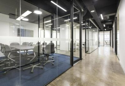 Professional glass-walled meeting room with a large table and grey mesh chairs.