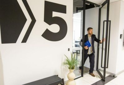 Building entrance with large graphic signage and a person walking through a glass door.