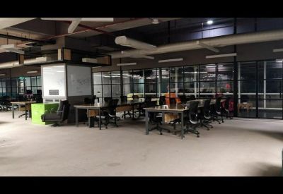 Open-plan workspace with multiple rows of desks and black ergonomic chairs