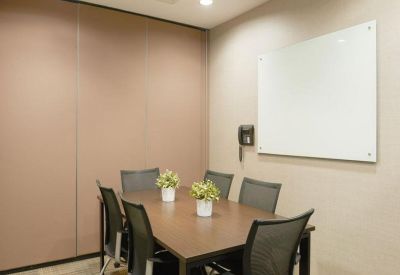 Small meeting room featuring a wooden table, glass whiteboard, and wall-mounted phone.