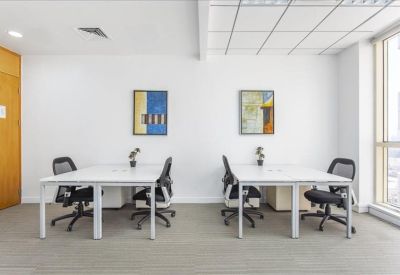 Spacious white office suite with two separate workstations and abstract wall art.