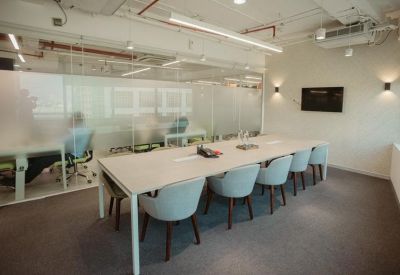 Modern meeting room with a long white table, light blue chairs, and a glass partition wall.