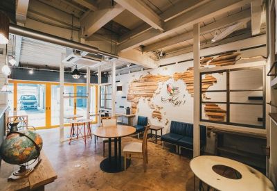 Spacious coworking area with wooden tables, blue seating, and a large world map wall feature.