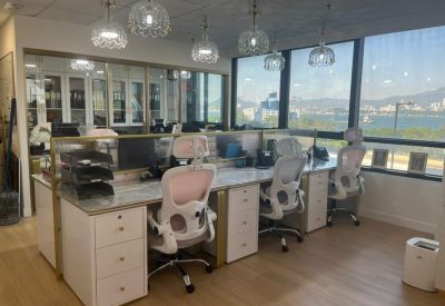 Open-plan workspace with multiple ergonomic white chairs and pendant lighting.