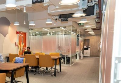 Spacious coworking area with tan leather chairs and exposed ceiling industrial design.