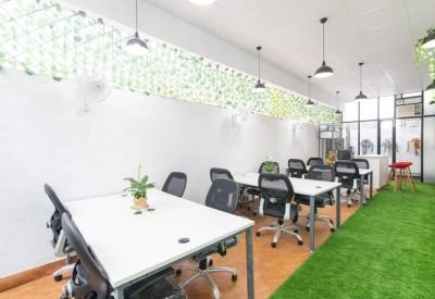 Open-plan office space featuring white desks and a section of artificial grass floor.
