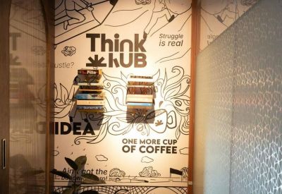 Modern wall art with the words Think Hub and motivational quotes next to a small bookshelf.