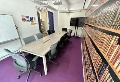 Meeting room with long table, grey chairs, and a library-themed feature wall.