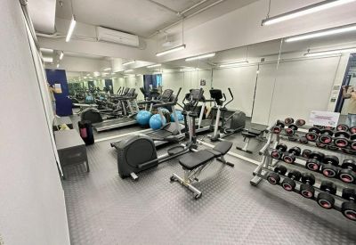Compact gym facility with treadmills, weight bench, and dumbbells.