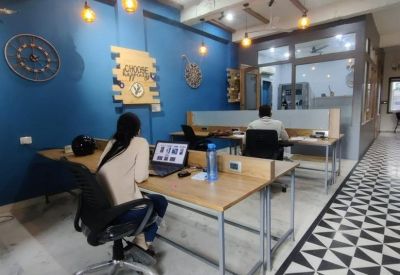 Open-plan office with wooden desks, blue feature walls, and geometric floor tiling.