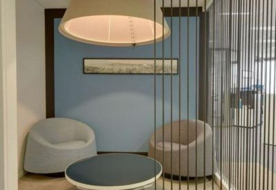 Private breakout nook with a large drum pendant light, blue accent wall, and curved armchairs.