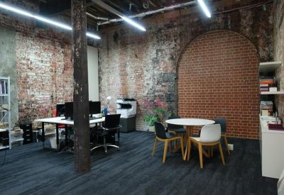 Communal breakout area featuring a round meeting table, modern chairs, and a decorative brick archway.
