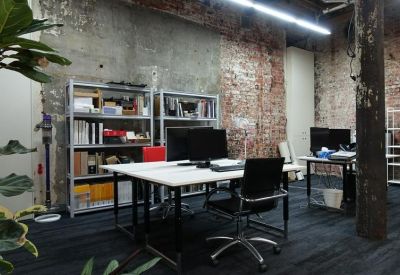 Spacious industrial-style office area with workstations, metal shelving, and a large rustic timber pillar.