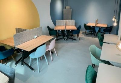 Bright breakout area featuring a yellow accent wall and pastel-colored seating.