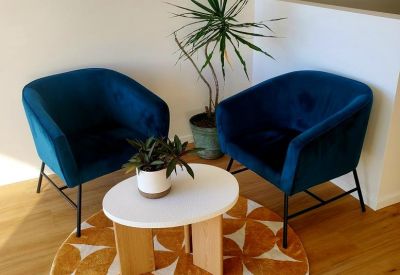 Bright breakout area with blue velvet armchairs and a geometric pattern rug.