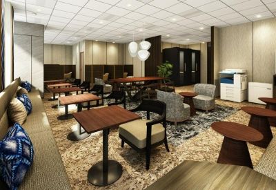 Coworking space with small wooden tables, blue patterned cushions, and a large multi-function printer.