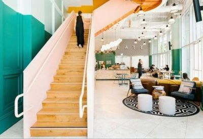 Bright lobby area featuring a light pink staircase and vibrant teal paneled walls.