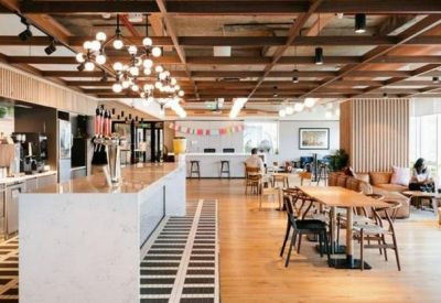 Large communal kitchen and cafe area with a white island, wooden ceiling, and dining tables.
