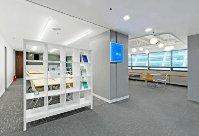Modern lobby area with a white geometric room divider and blue digital signage.