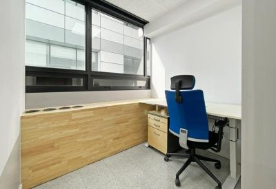 Private window-side office with a blue ergonomic chair and light wood accents.