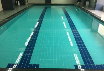 Indoor lap pool with turquoise water and dark blue lane markers.