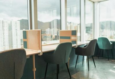 Window-facing workstations with privacy dividers and grey armchairs.
