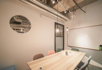 Bright meeting room with a light wood table and a whiteboard.