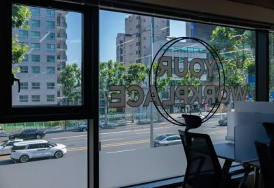 Coworking area featuring a window with a city view and Your Workplace branding on the glass.