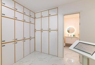 Locker room area with floor-to-ceiling white storage units and marble-style flooring.