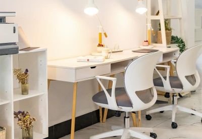 Bright workspace featuring a long white desk with two ergonomic chairs and task lighting.
