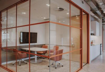 Meeting room with glass walls, orange frame, and round table.