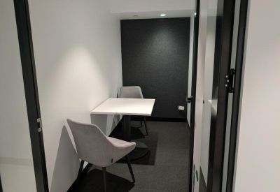 Private glass-enclosed focus room with a small table and two grey chairs.