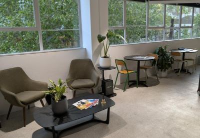 Bright breakout area with cafe-style seating and large windows overlooking trees.