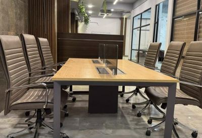 Modern meeting room with a light wood table and ergonomic grey chairs.