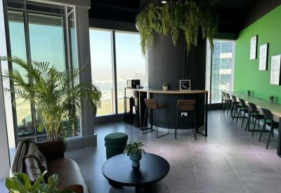 Bright breakout area with a curved coffee bar, hanging plants, and floor-to-ceiling windows.