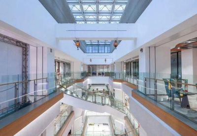 Multi-level atrium featuring a glass ceiling and white geometric balconies.