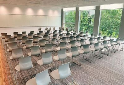 Training room filled with rows of modern grey chairs facing a whiteboard.