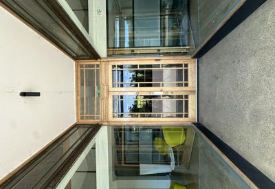 Modern glass-walled meeting room with timber framing and lime green chairs.