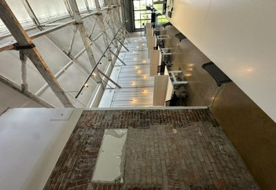 High-angle view of an industrial office corridor with exposed brickwork and timber trusses.