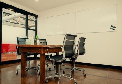 Professional meeting room with wooden table and two large whiteboards.