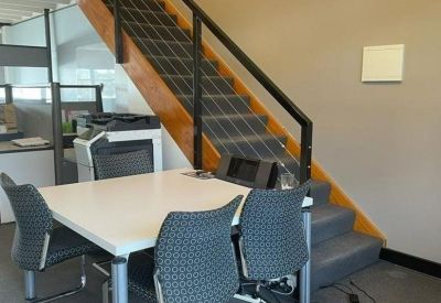 Compact meeting area with a white table and chairs located beneath a wooden staircase.