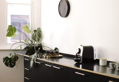 Modern black kitchen cabinetry with a coffee machine and large window.