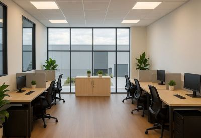 Open-plan office with wooden flooring, modern workstations, and indoor plants.