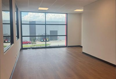 Bright, empty office space with large windows and warm wood-style flooring.
