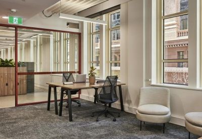 Bright glass-walled office suite with a wooden desk and modern ergonomic chairs.