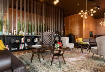Lounge area featuring plush armchairs, a large patterned rug, and decorative wooden slat partitions.