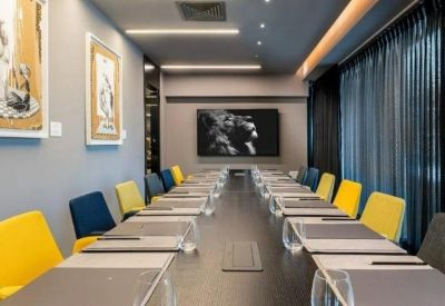 Modern conference room with a long dark table and vibrant yellow and blue chairs.