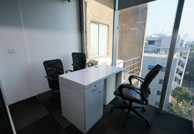 Private corner office with a white desk, ergonomic chairs, and large window views.